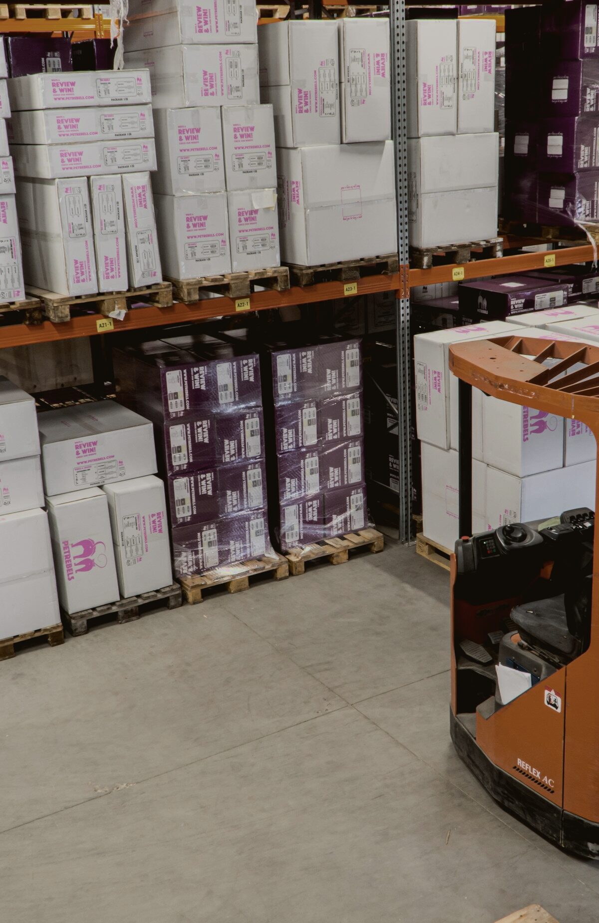 Warehouse racking with pallets and an electric forklift in the aisle.